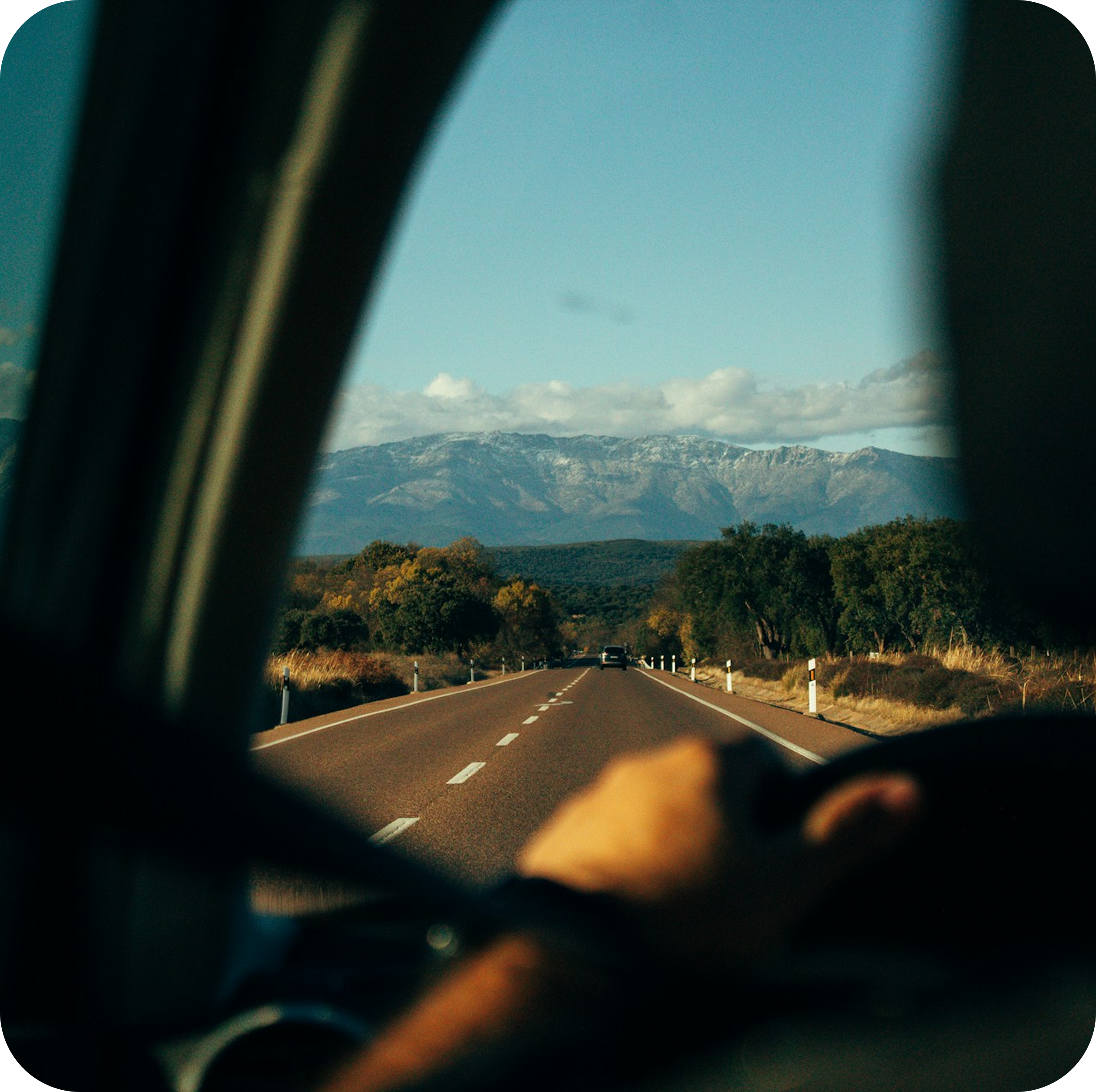View through car window of road leading to mountains